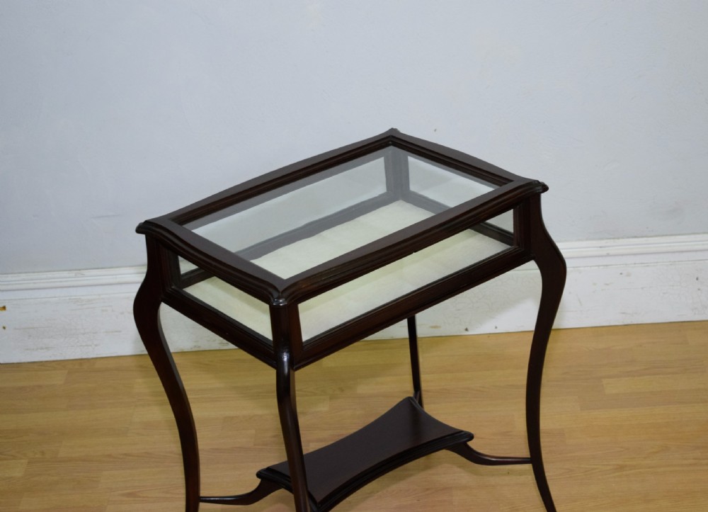 A Victorian dark mahogany bijouterie display table featuring four cabriole legs, clear glass side panels, a hinged glazed top, and a lower curved shelf. View XV