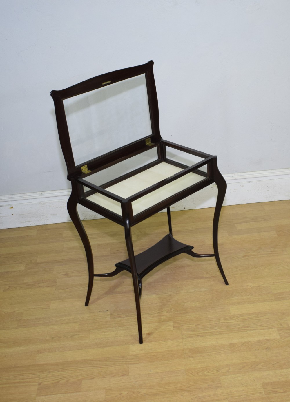 A Victorian dark mahogany bijouterie display table featuring four cabriole legs, clear glass side panels, a hinged glazed top, and a lower curved shelf. View XVII