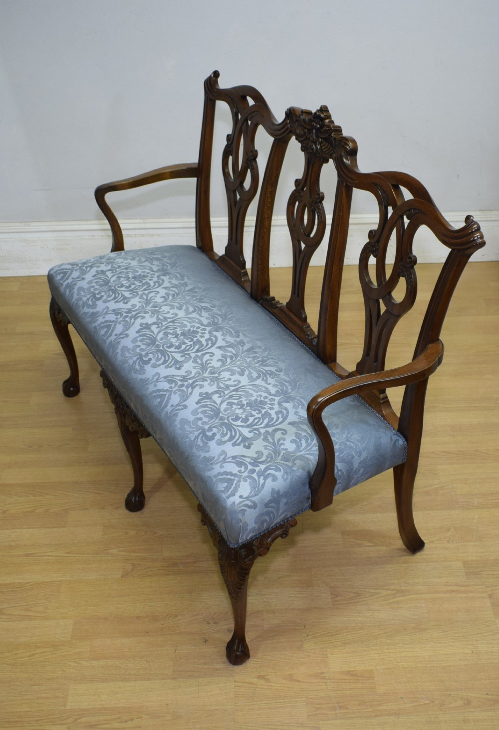An early 20th-century mahogany triple chair-back Chippendale style settee featuring carved pierced back splats, light blue patterned upholstery, and cabriole legs with ball-and-claw feet. View III