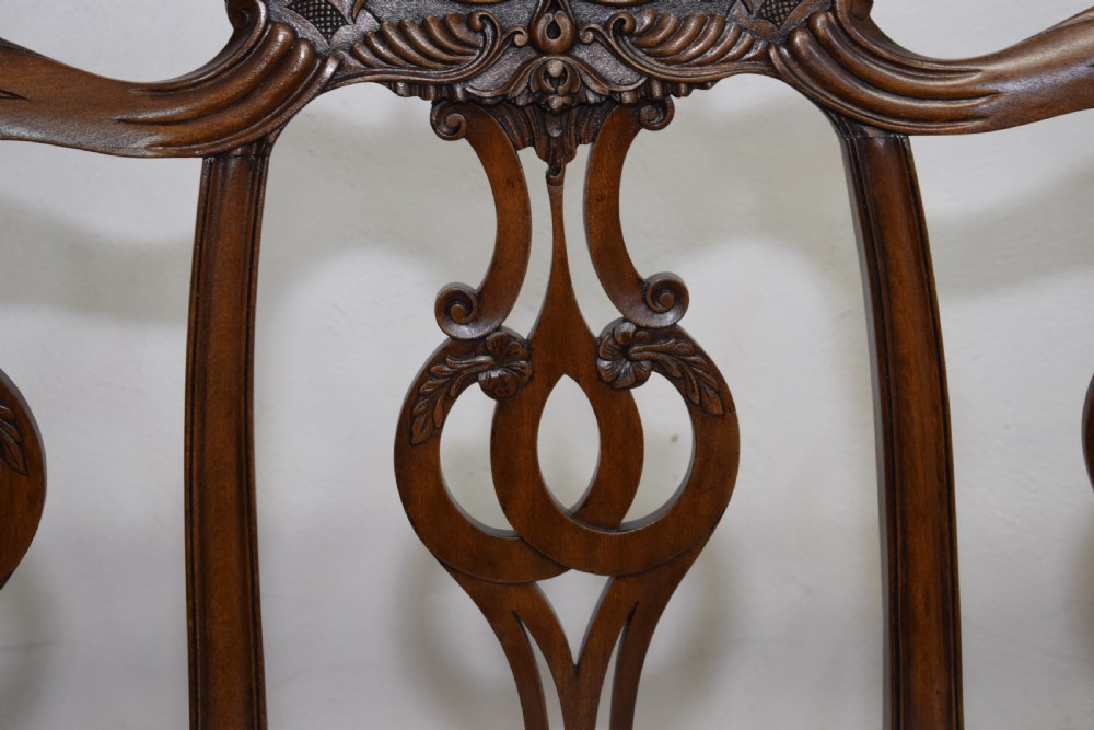 An early 20th-century mahogany triple chair-back Chippendale style settee featuring carved pierced back splats, light blue patterned upholstery, and cabriole legs with ball-and-claw feet. View VIII
