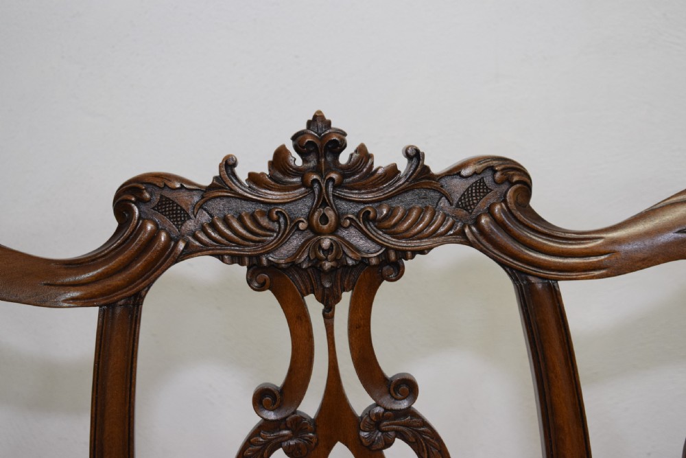 An early 20th-century mahogany triple chair-back Chippendale style settee featuring carved pierced back splats, light blue patterned upholstery, and cabriole legs with ball-and-claw feet. View IX