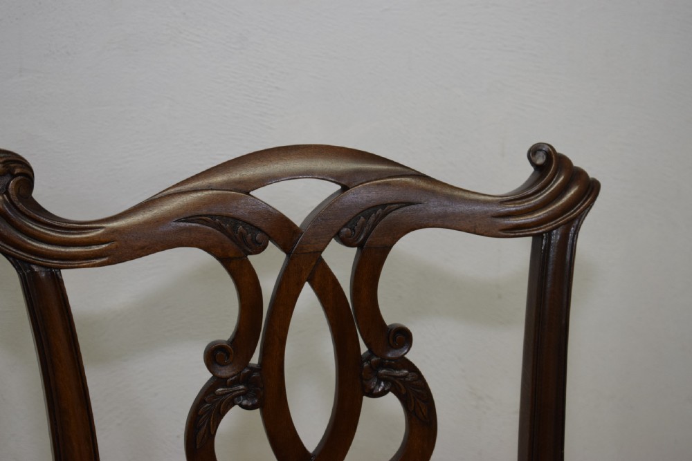 An early 20th-century mahogany triple chair-back Chippendale style settee featuring carved pierced back splats, light blue patterned upholstery, and cabriole legs with ball-and-claw feet. View X