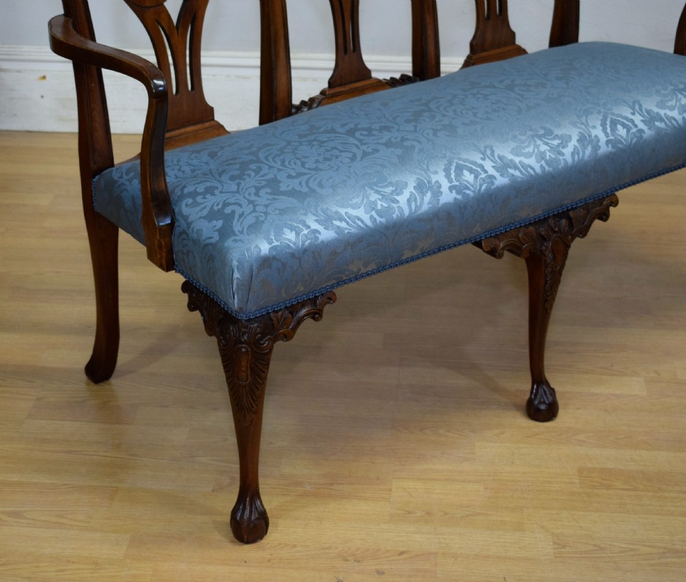 An early 20th-century mahogany triple chair-back Chippendale style settee featuring carved pierced back splats, light blue patterned upholstery, and cabriole legs with ball-and-claw feet. View XIII