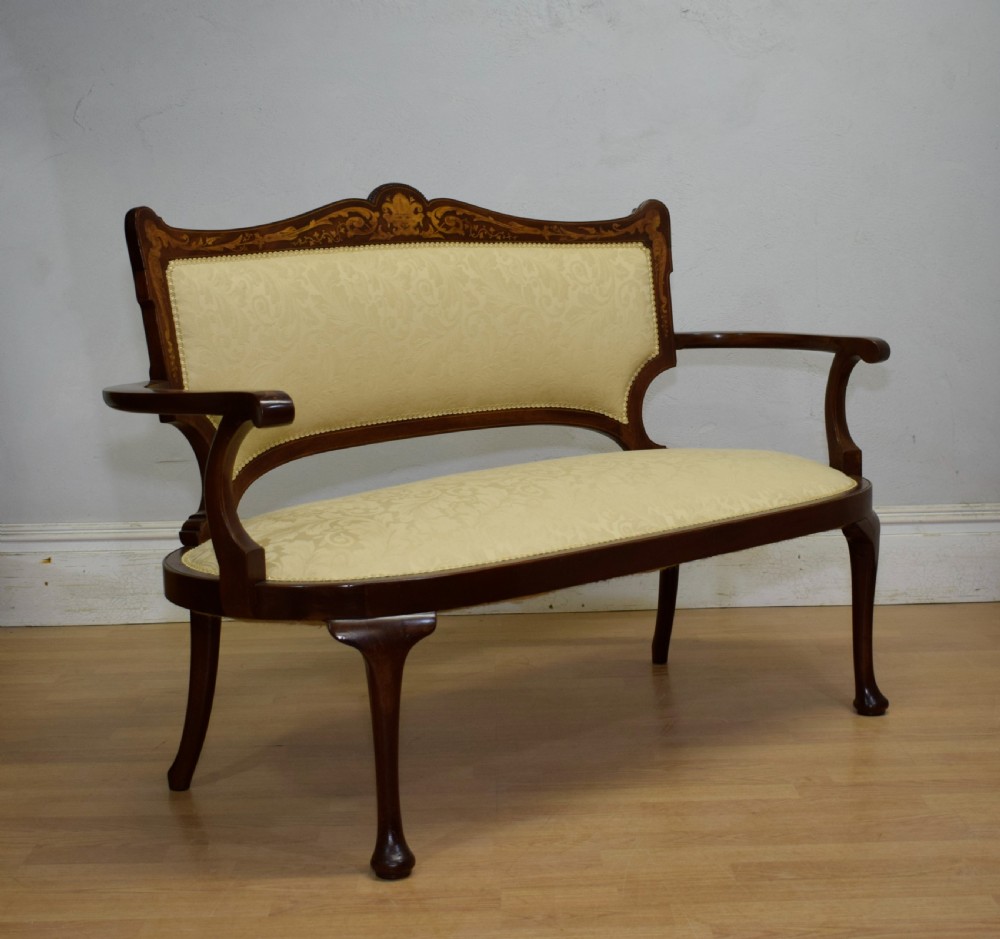 A Victorian dark mahogany settee with floral marquetry inlay along the crest rail and cream damask upholstered seat and backrest. View II
