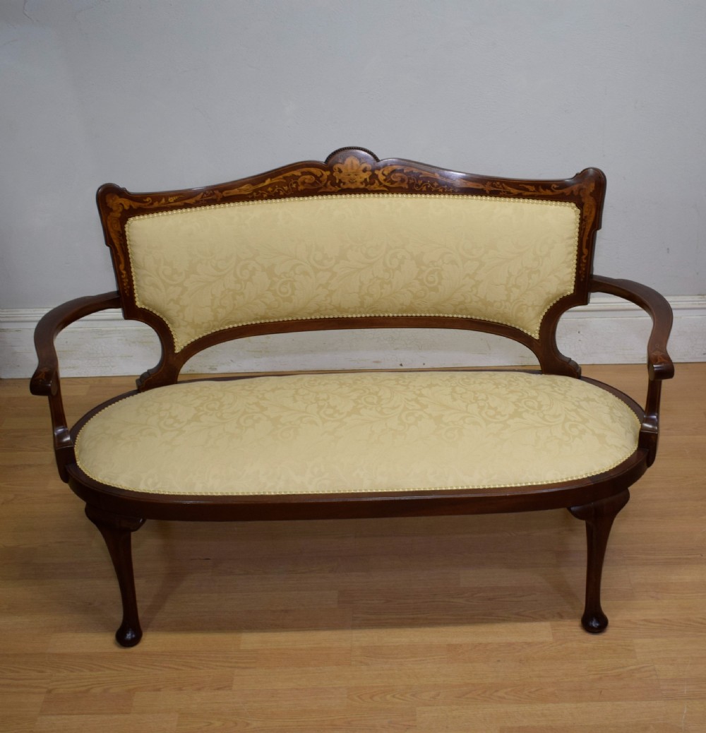 A Victorian dark mahogany settee with floral marquetry inlay along the crest rail and cream damask upholstered seat and backrest. View V