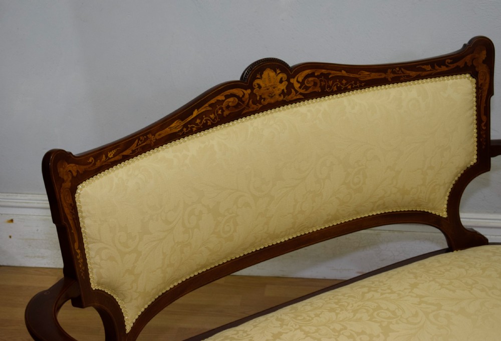 A Victorian dark mahogany settee with floral marquetry inlay along the crest rail and cream damask upholstered seat and backrest. View VI