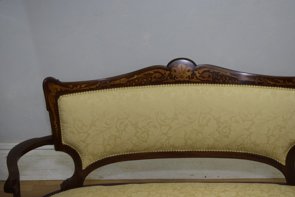 A Victorian dark mahogany settee with floral marquetry inlay along the crest rail and cream damask upholstered seat and backrest. View X