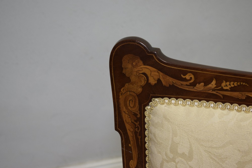 A Victorian dark mahogany settee with floral marquetry inlay along the crest rail and cream damask upholstered seat and backrest. View XIX