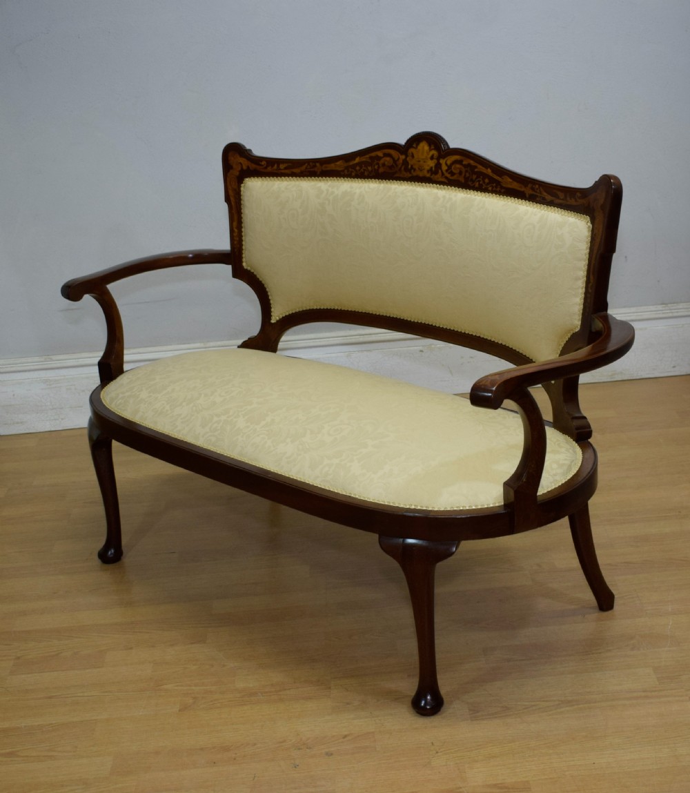 A Victorian dark mahogany settee with floral marquetry inlay along the crest rail and cream damask upholstered seat and backrest. View XX