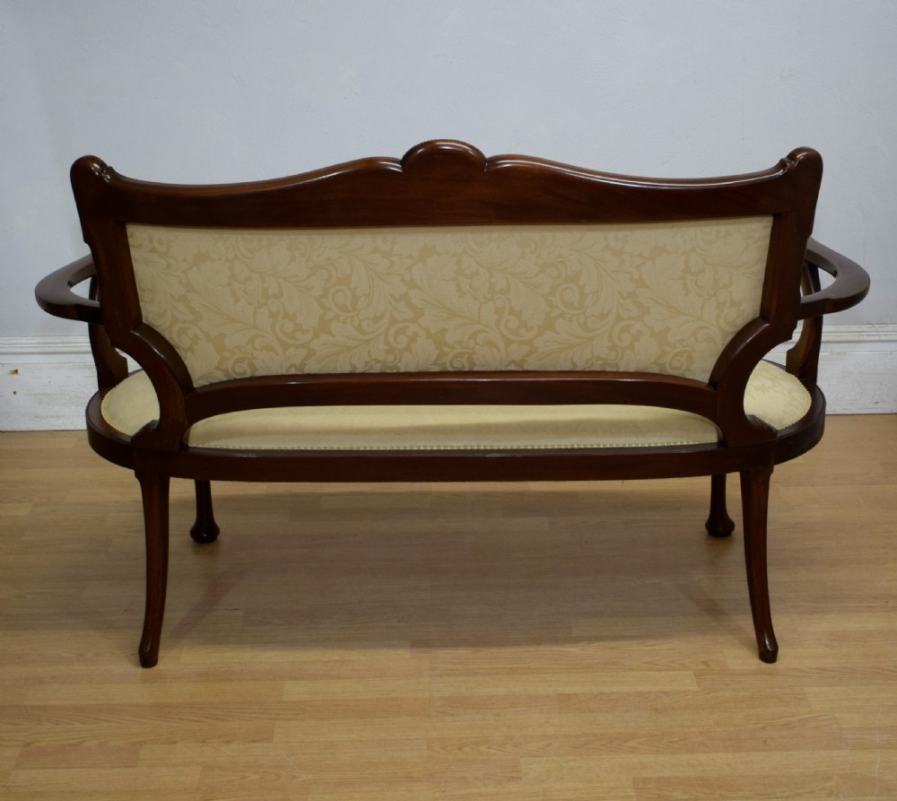 A Victorian dark mahogany settee with floral marquetry inlay along the crest rail and cream damask upholstered seat and backrest. View XXV