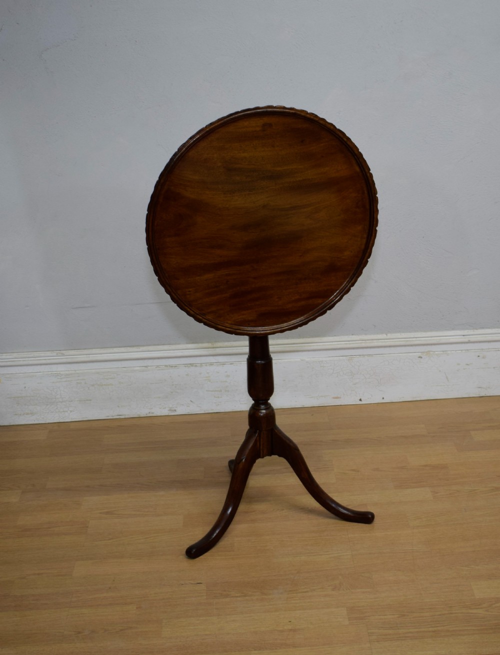 A dark mahogany Georgian tripod table featuring a circular top with a moulded rim, a turned central stem, and three splayed cabriole legs. View II