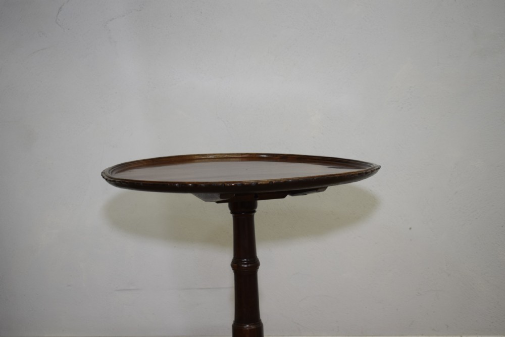 A dark mahogany Georgian tripod table featuring a circular top with a moulded rim, a turned central stem, and three splayed cabriole legs. View XVI