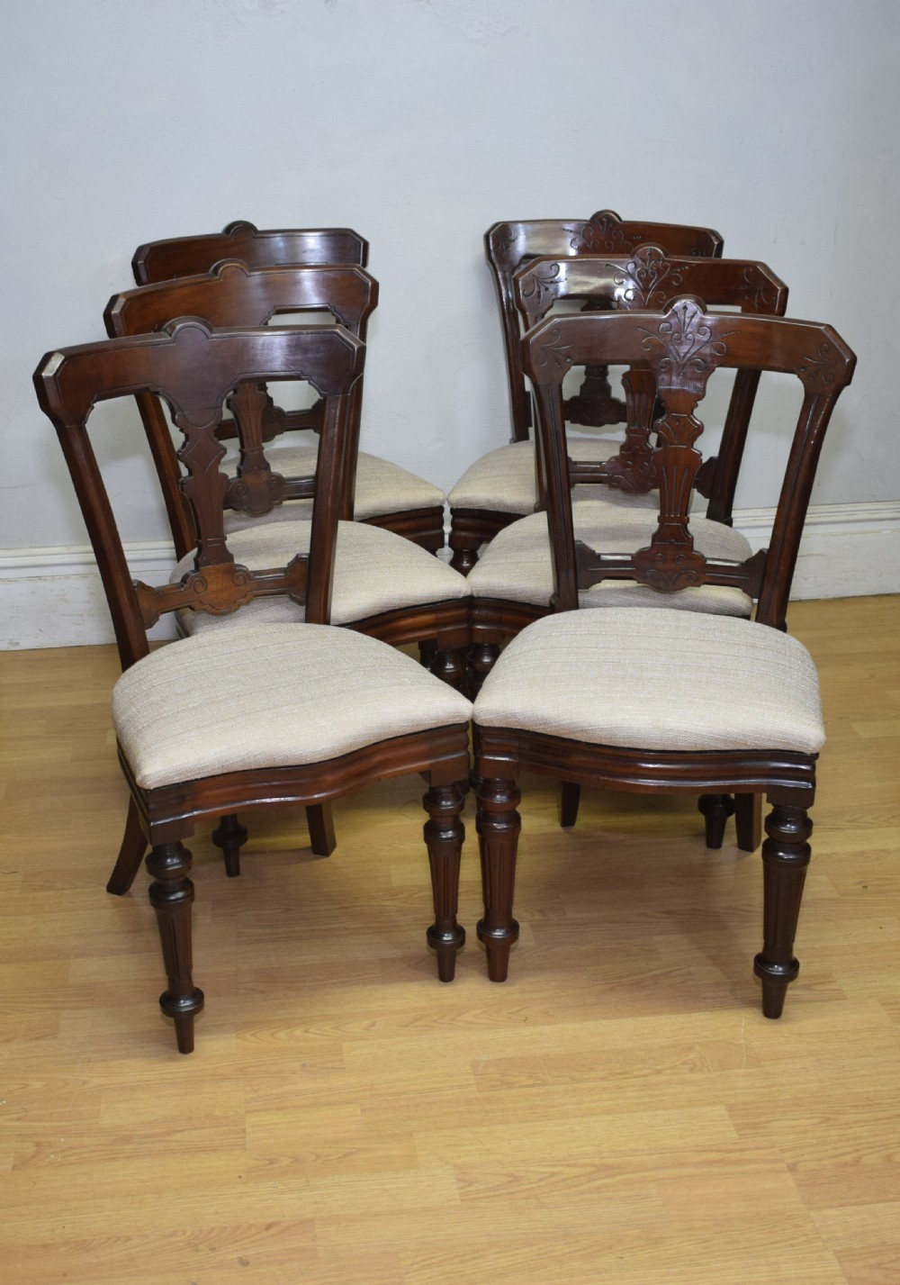 A set of six Victorian mahogany dining chairs featuring carved open backs, turned front legs, and neutral upholstered seats. View IV