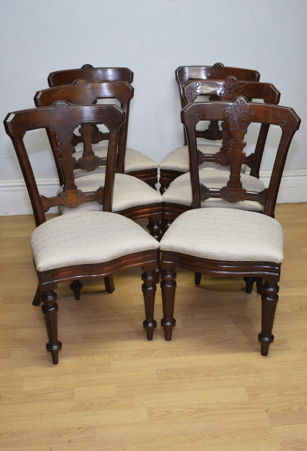 A set of six Victorian mahogany dining chairs featuring carved open backs, turned front legs, and neutral upholstered seats. View V