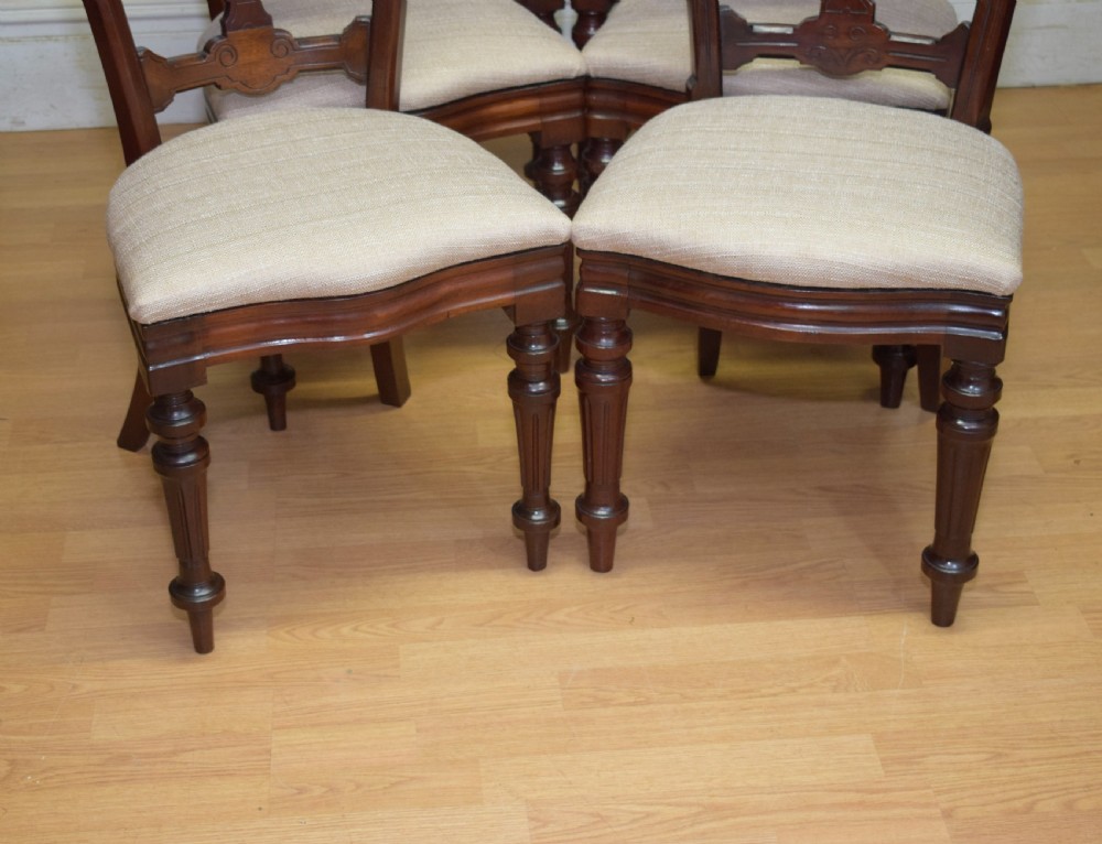 A set of six Victorian mahogany dining chairs featuring carved open backs, turned front legs, and neutral upholstered seats. View VI