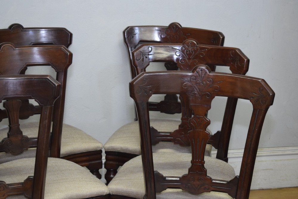A set of six Victorian mahogany dining chairs featuring carved open backs, turned front legs, and neutral upholstered seats. View VII