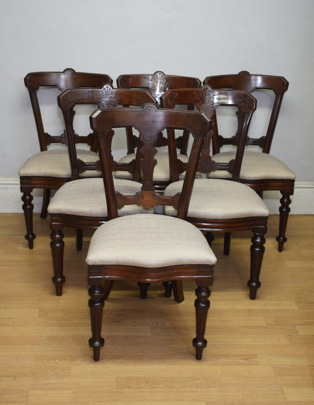 A set of six Victorian mahogany dining chairs featuring carved open backs, turned front legs, and neutral upholstered seats. View XV