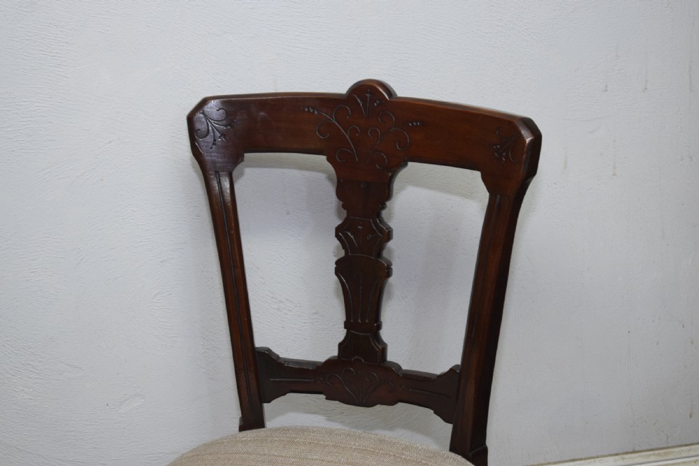 A set of six Victorian mahogany dining chairs featuring carved open backs, turned front legs, and neutral upholstered seats. View XX
