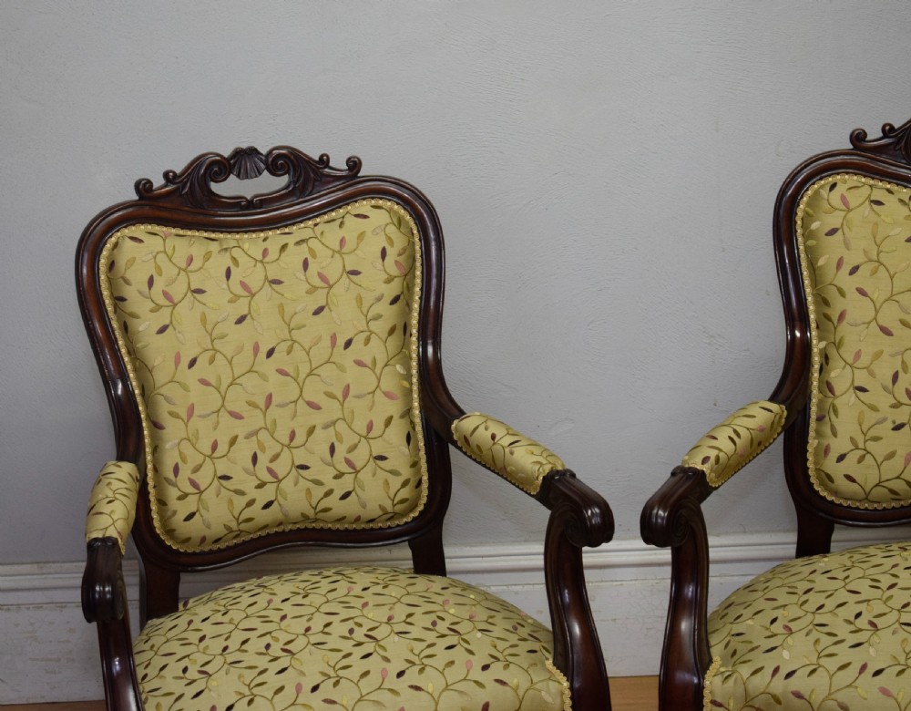 A pair of 19th-century French armchairs featuring carved dark wood frames, cabriole legs with castors, and light green embroidered fabric upholstery. View V