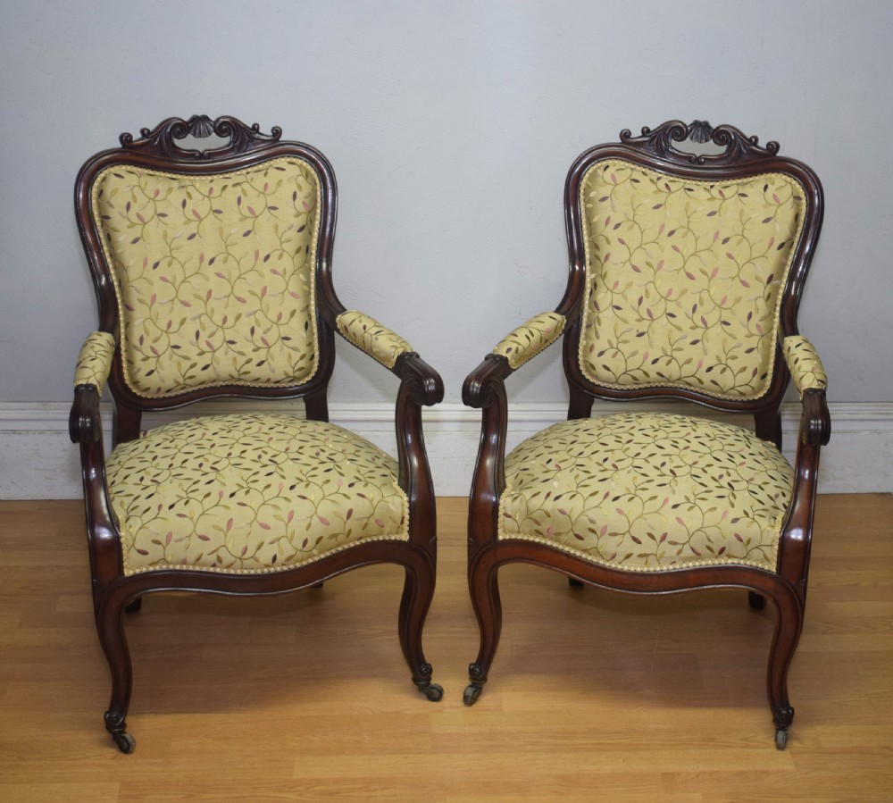 A pair of 19th-century French armchairs featuring carved dark wood frames, cabriole legs with castors, and light green embroidered fabric upholstery. View VI