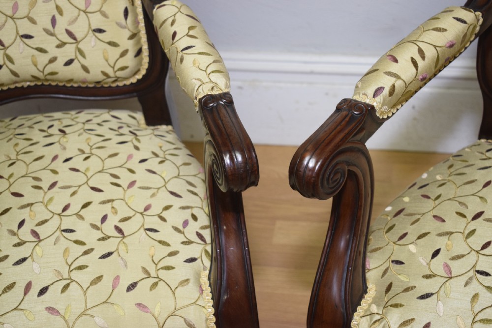A pair of 19th-century French armchairs featuring carved dark wood frames, cabriole legs with castors, and light green embroidered fabric upholstery. View X