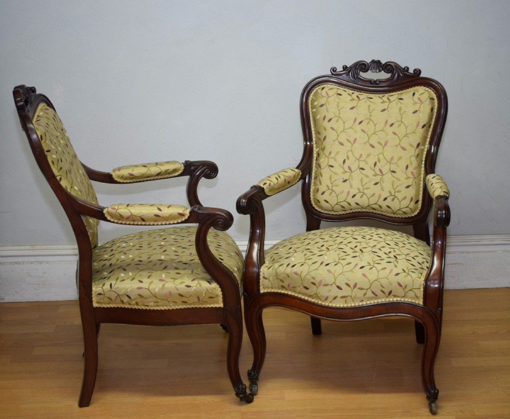 A pair of 19th-century French armchairs featuring carved dark wood frames, cabriole legs with castors, and light green embroidered fabric upholstery. View XVII