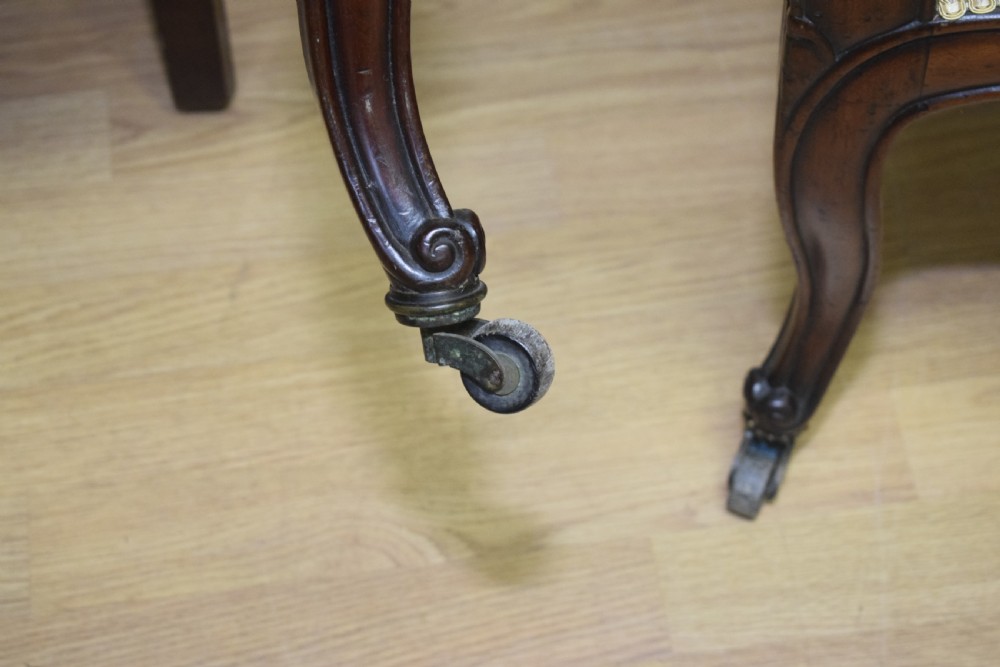 A pair of 19th-century French armchairs featuring carved dark wood frames, cabriole legs with castors, and light green embroidered fabric upholstery. View XXVI