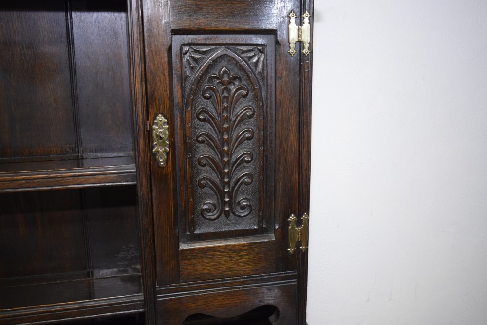 A dark carved oak Jacobean style Welsh dresser featuring an upper plate rack with side cupboard doors over a lower sideboard base with three carved drawers and turned legs. View VIII