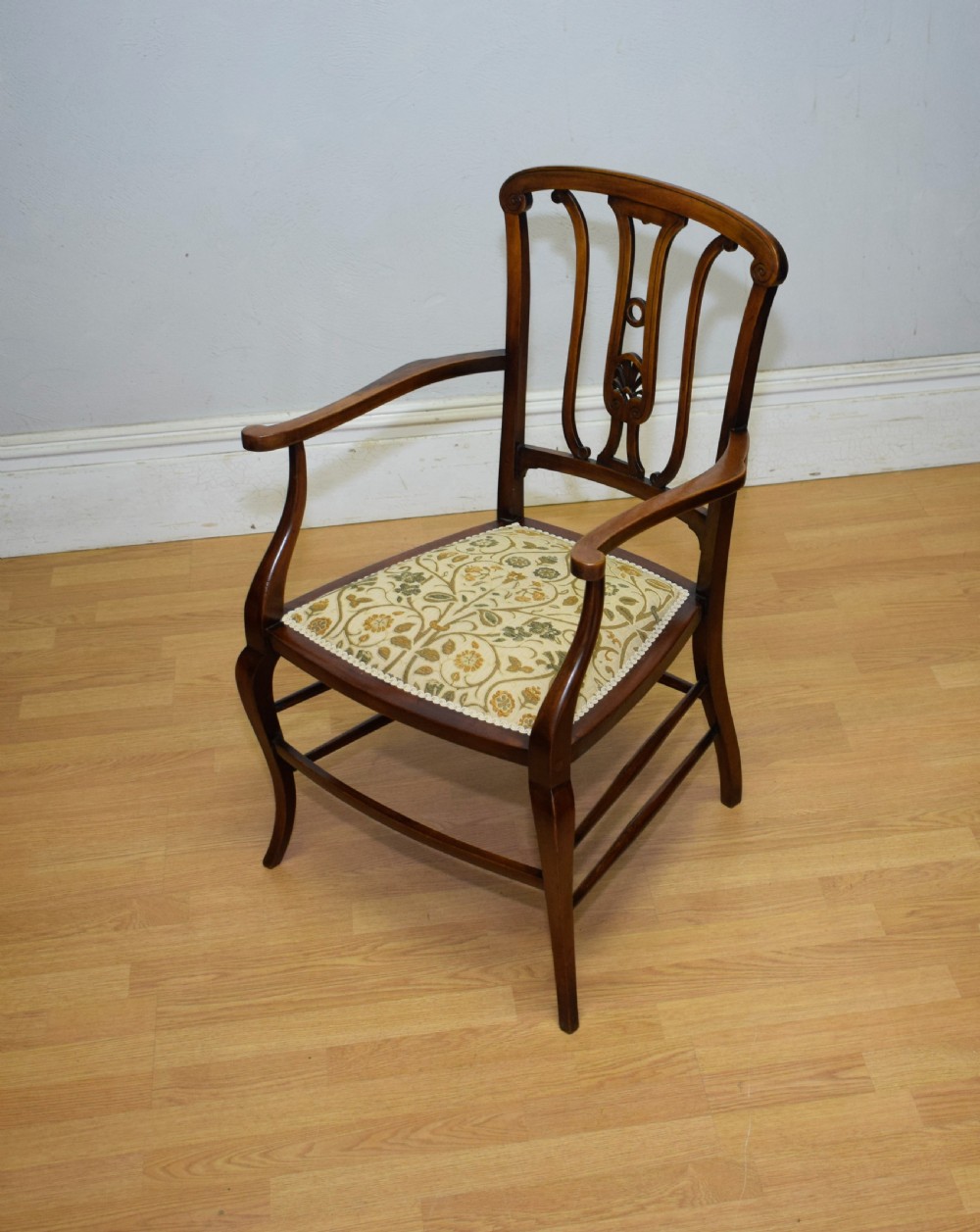 An Edwardian mahogany open armchair featuring a carved splat back, shaped armrests, and floral pattern fabric upholstery. View II