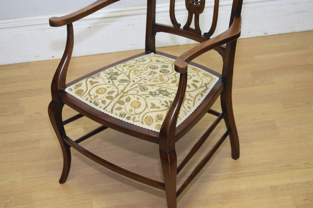 An Edwardian mahogany open armchair featuring a carved splat back, shaped armrests, and floral pattern fabric upholstery. View III