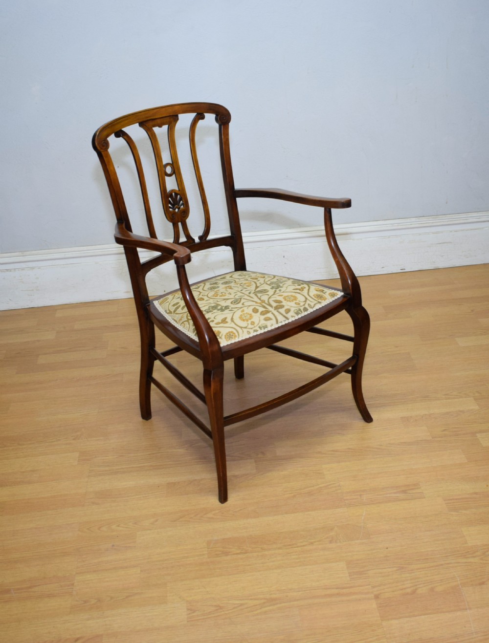 An Edwardian mahogany open armchair featuring a carved splat back, shaped armrests, and floral pattern fabric upholstery. View VI