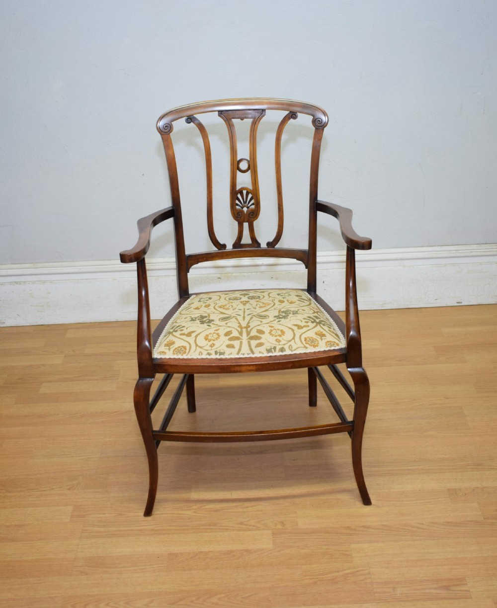 An Edwardian mahogany open armchair featuring a carved splat back, shaped armrests, and floral pattern fabric upholstery. View VII