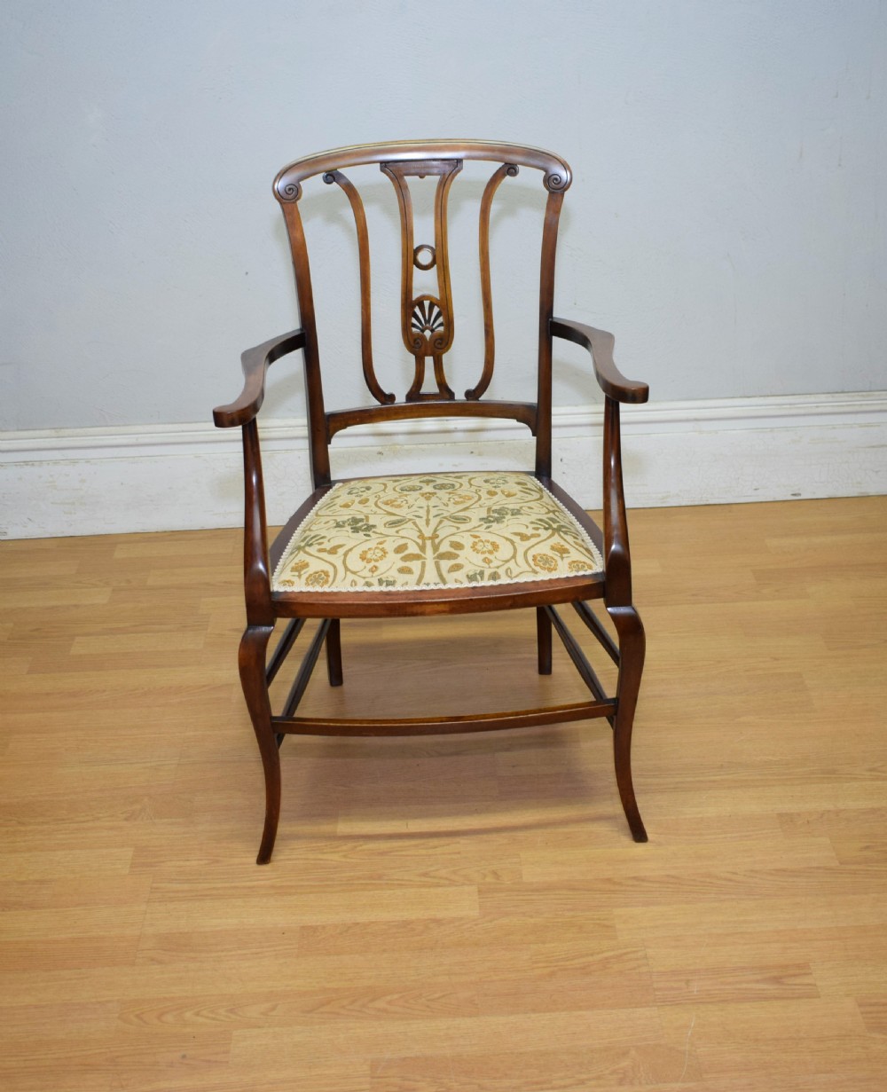 An Edwardian mahogany open armchair featuring a carved splat back, shaped armrests, and floral pattern fabric upholstery. View IX
