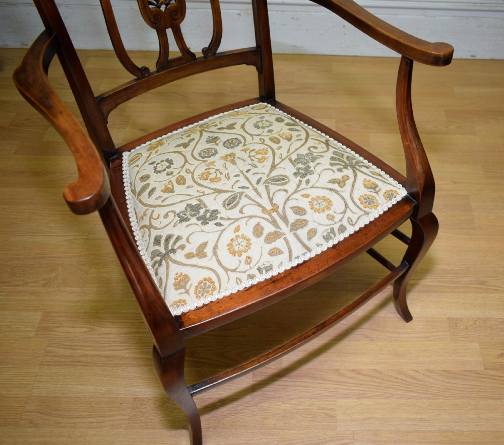 An Edwardian mahogany open armchair featuring a carved splat back, shaped armrests, and floral pattern fabric upholstery. View XV