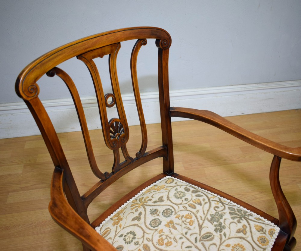 An Edwardian mahogany open armchair featuring a carved splat back, shaped armrests, and floral pattern fabric upholstery. View XVI