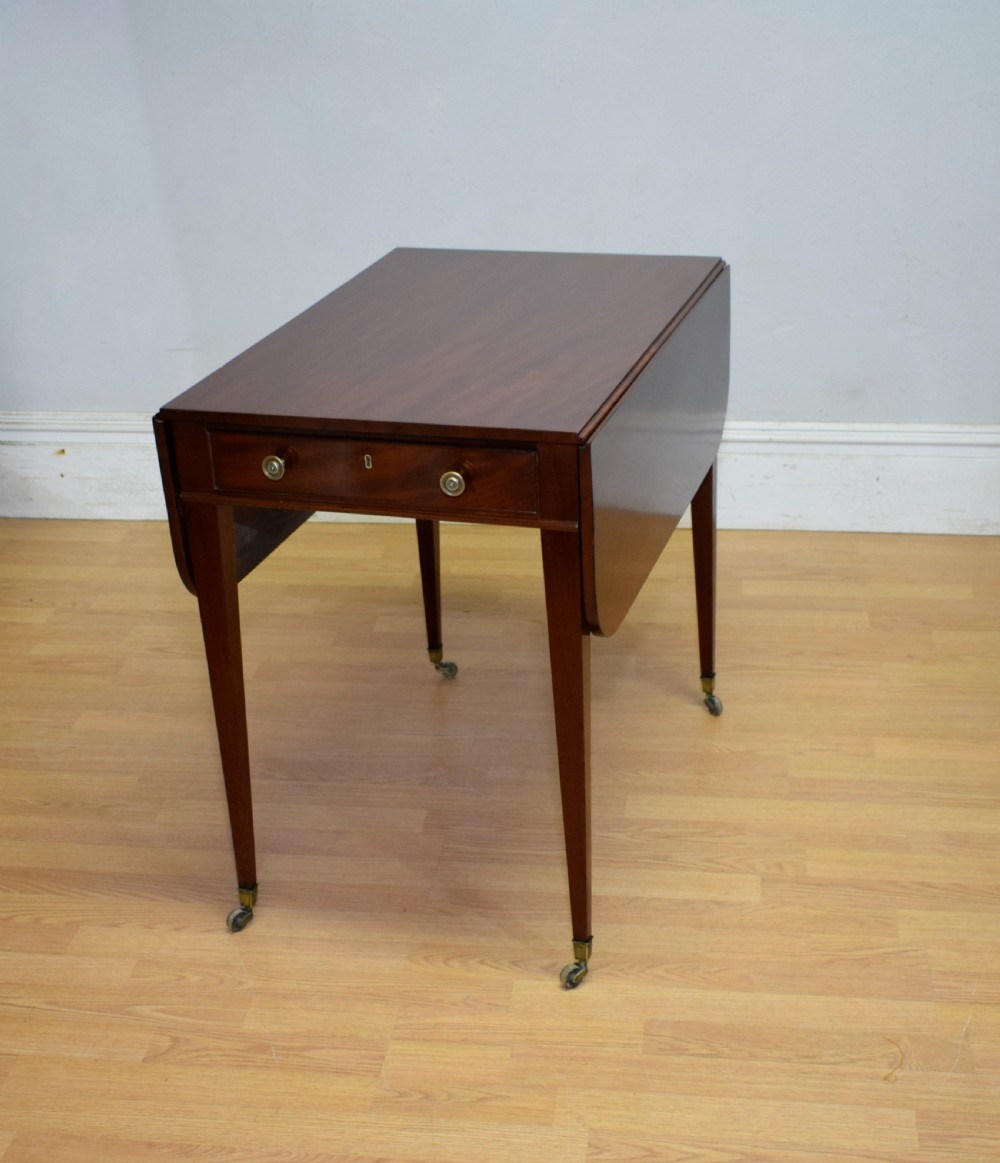 A Regency mahogany Pembroke table featuring dual drop-leaf sides, a front drawer with two brass pull knobs, square tapered legs, and brass brass castors. View III
