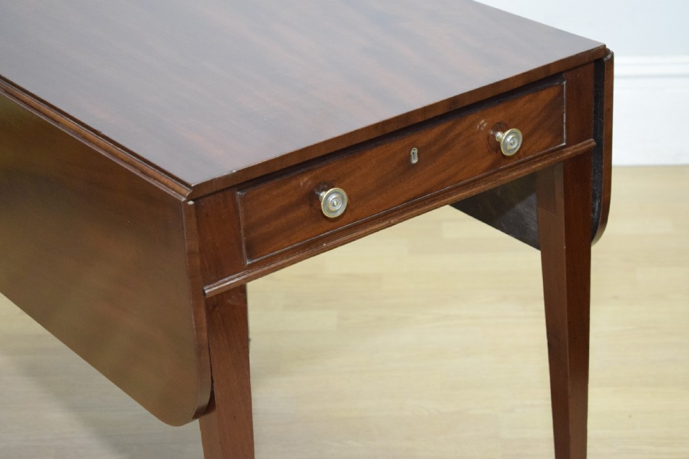 A Regency mahogany Pembroke table featuring dual drop-leaf sides, a front drawer with two brass pull knobs, square tapered legs, and brass brass castors. View V