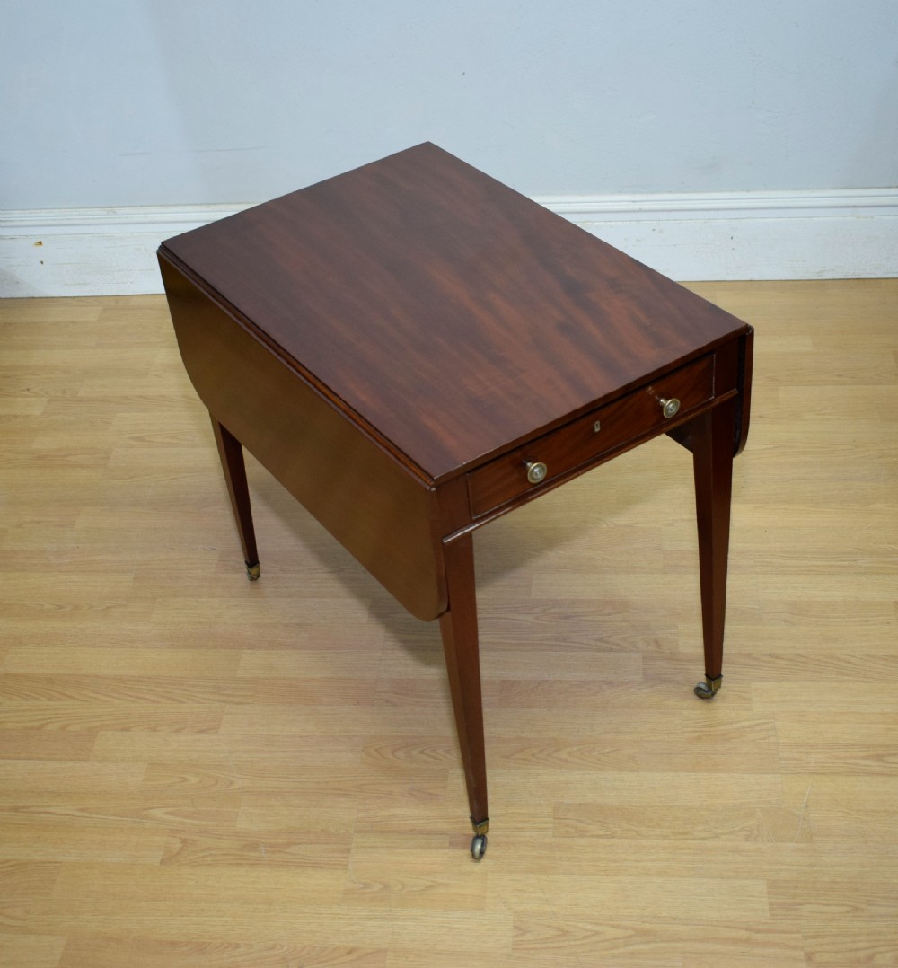 A Regency mahogany Pembroke table featuring dual drop-leaf sides, a front drawer with two brass pull knobs, square tapered legs, and brass brass castors. View VIII