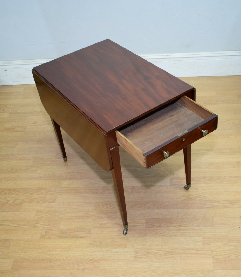 A Regency mahogany Pembroke table featuring dual drop-leaf sides, a front drawer with two brass pull knobs, square tapered legs, and brass brass castors. View XII