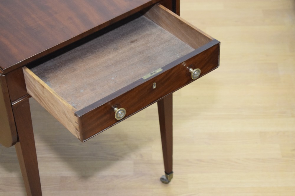 A Regency mahogany Pembroke table featuring dual drop-leaf sides, a front drawer with two brass pull knobs, square tapered legs, and brass brass castors. View XIV