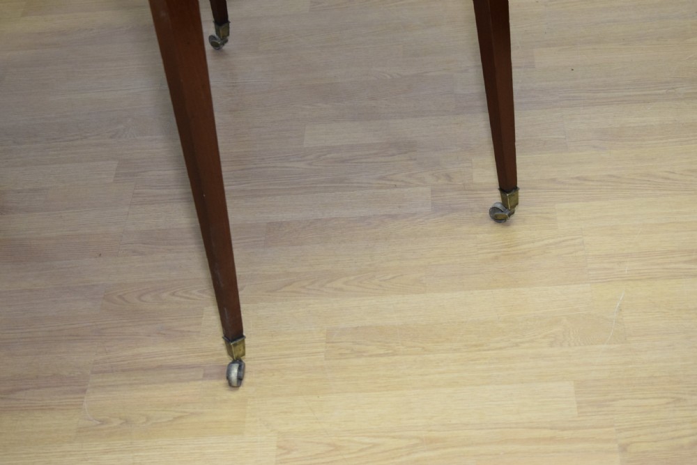 A Regency mahogany Pembroke table featuring dual drop-leaf sides, a front drawer with two brass pull knobs, square tapered legs, and brass brass castors. View XVI