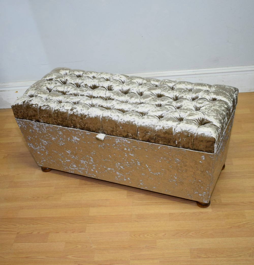 A rectangular upholstered storage ottoman in champagne crushed velvet with a deep buttoned tufted lid and small wooden feet. View II