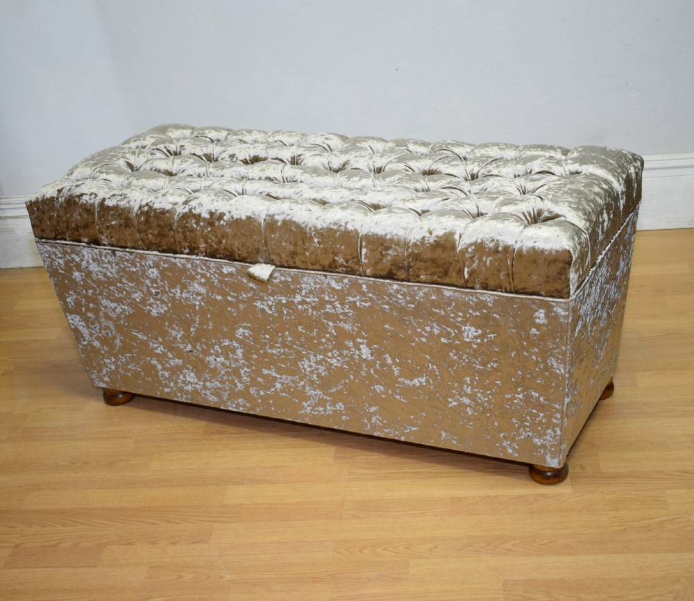 A rectangular upholstered storage ottoman in champagne crushed velvet with a deep buttoned tufted lid and small wooden feet. View III