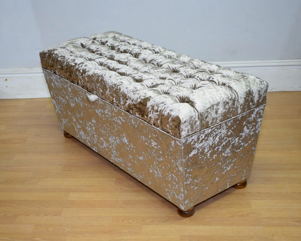 A rectangular upholstered storage ottoman in champagne crushed velvet with a deep buttoned tufted lid and small wooden feet. View V
