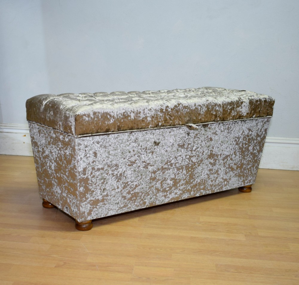 A rectangular upholstered storage ottoman in champagne crushed velvet with a deep buttoned tufted lid and small wooden feet. View XII