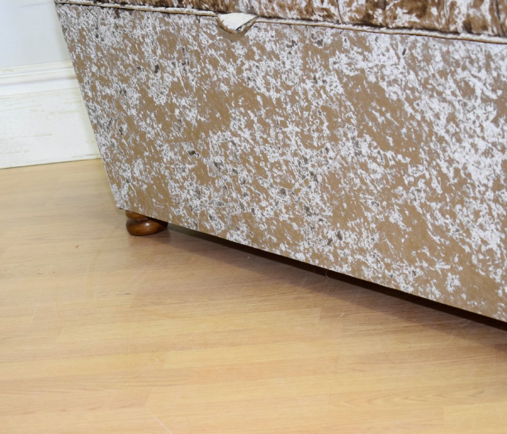 A rectangular upholstered storage ottoman in champagne crushed velvet with a deep buttoned tufted lid and small wooden feet. View XVIII