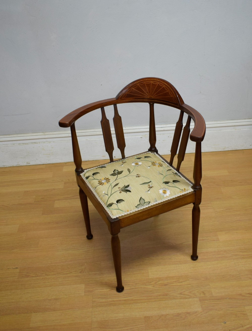 An Edwardian mahogany corner chair featuring a curved top rail with fan inlay, turned spindles, and a floral upholstered square seat. View II