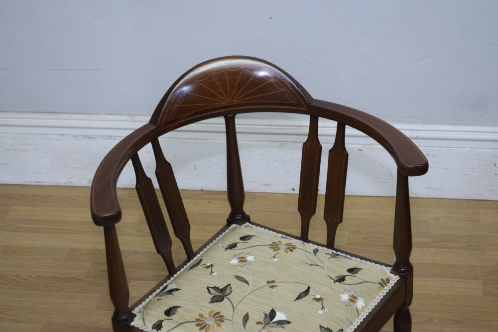 An Edwardian mahogany corner chair featuring a curved top rail with fan inlay, turned spindles, and a floral upholstered square seat. View III