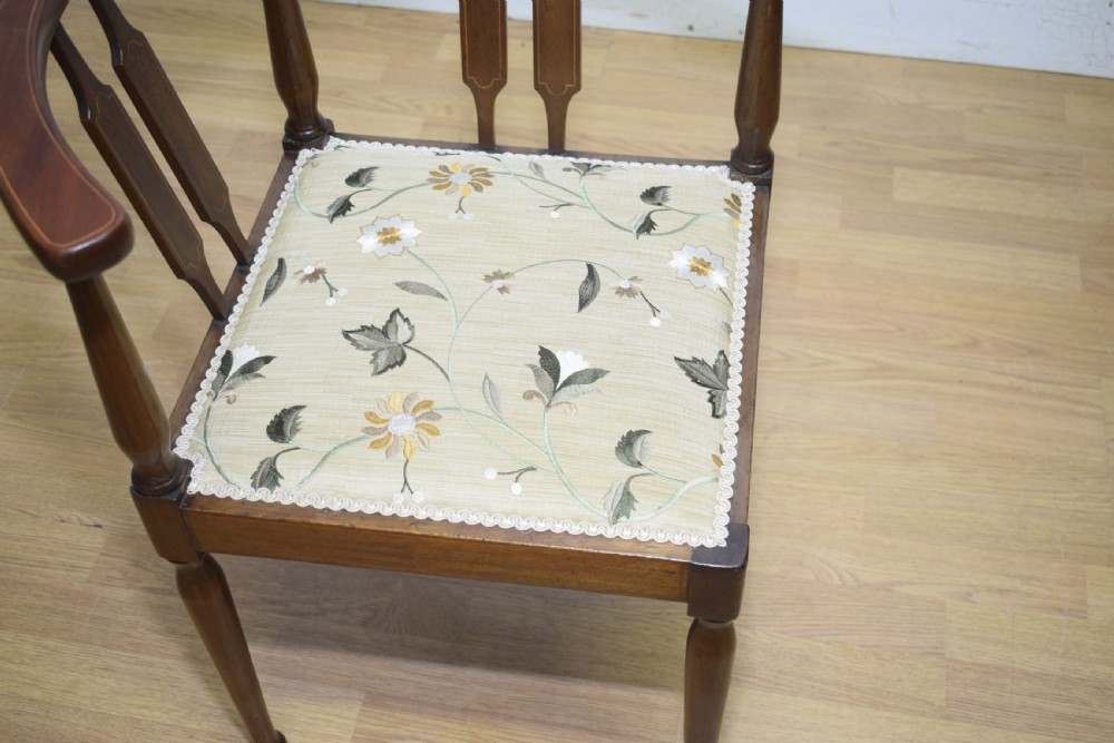 An Edwardian mahogany corner chair featuring a curved top rail with fan inlay, turned spindles, and a floral upholstered square seat. View IV
