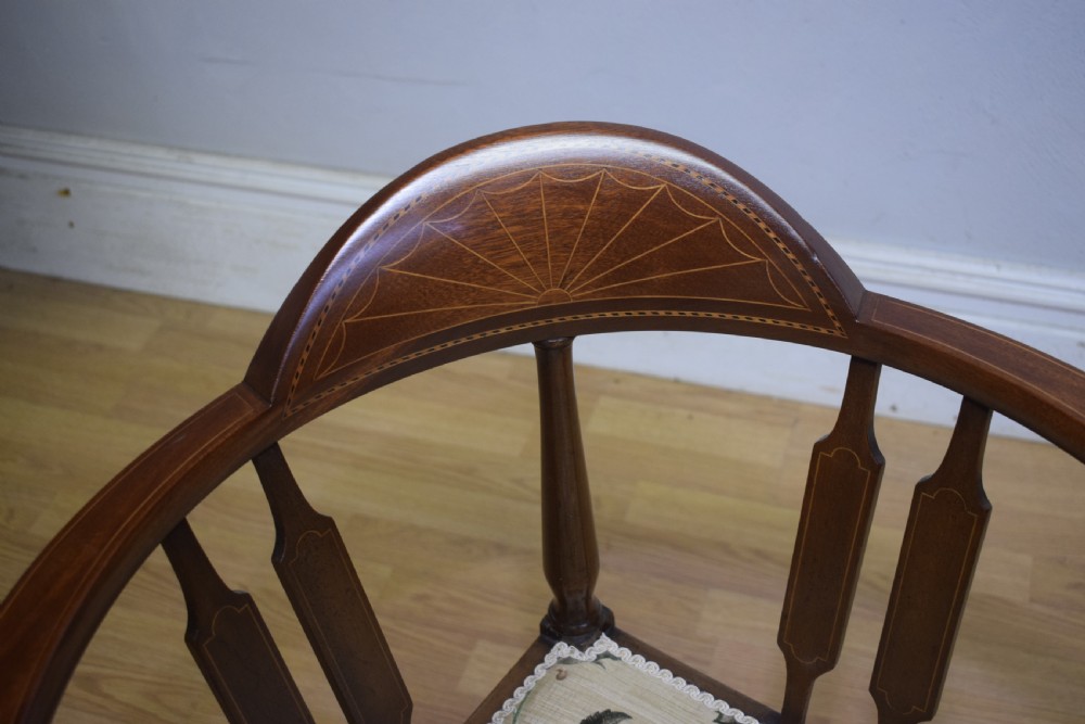 An Edwardian mahogany corner chair featuring a curved top rail with fan inlay, turned spindles, and a floral upholstered square seat. View VI